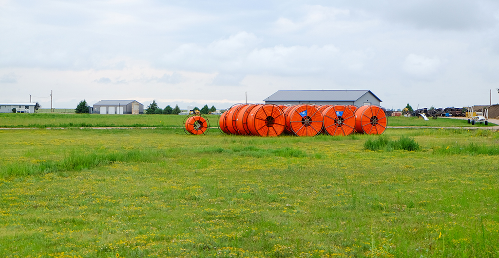 Orange cable for broadband connections on a steel cable drum on a field 11122019